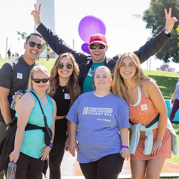 Six Best Buddies Friendship Walk Participants. They are outside on a sunny day wearing black t-shirts that say Inclusion Without Limits.