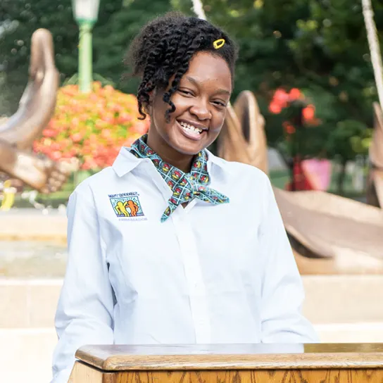 A female Best Buddies Ambassador giving a speech at a podium